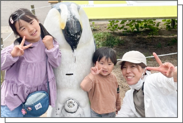 ペンギンの像の隣でピースをするのお母さんと兄弟